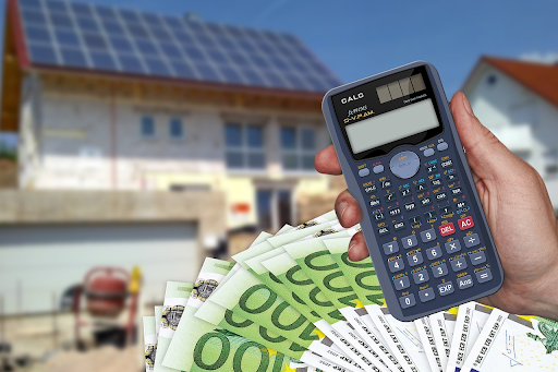 Calculator and currency notes in front of an open house, symbolising how much a buyer’s agent costs