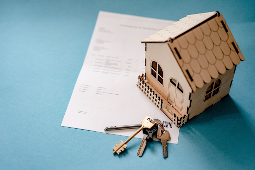 A set of house keys, a miniature house, and a rental agreement document, symbolising property ownership and management decisions.